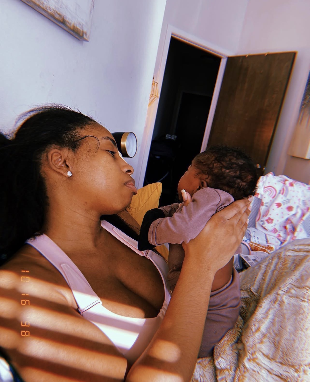 Mother lying in morning light holding her baby close, foreheads nearly touching